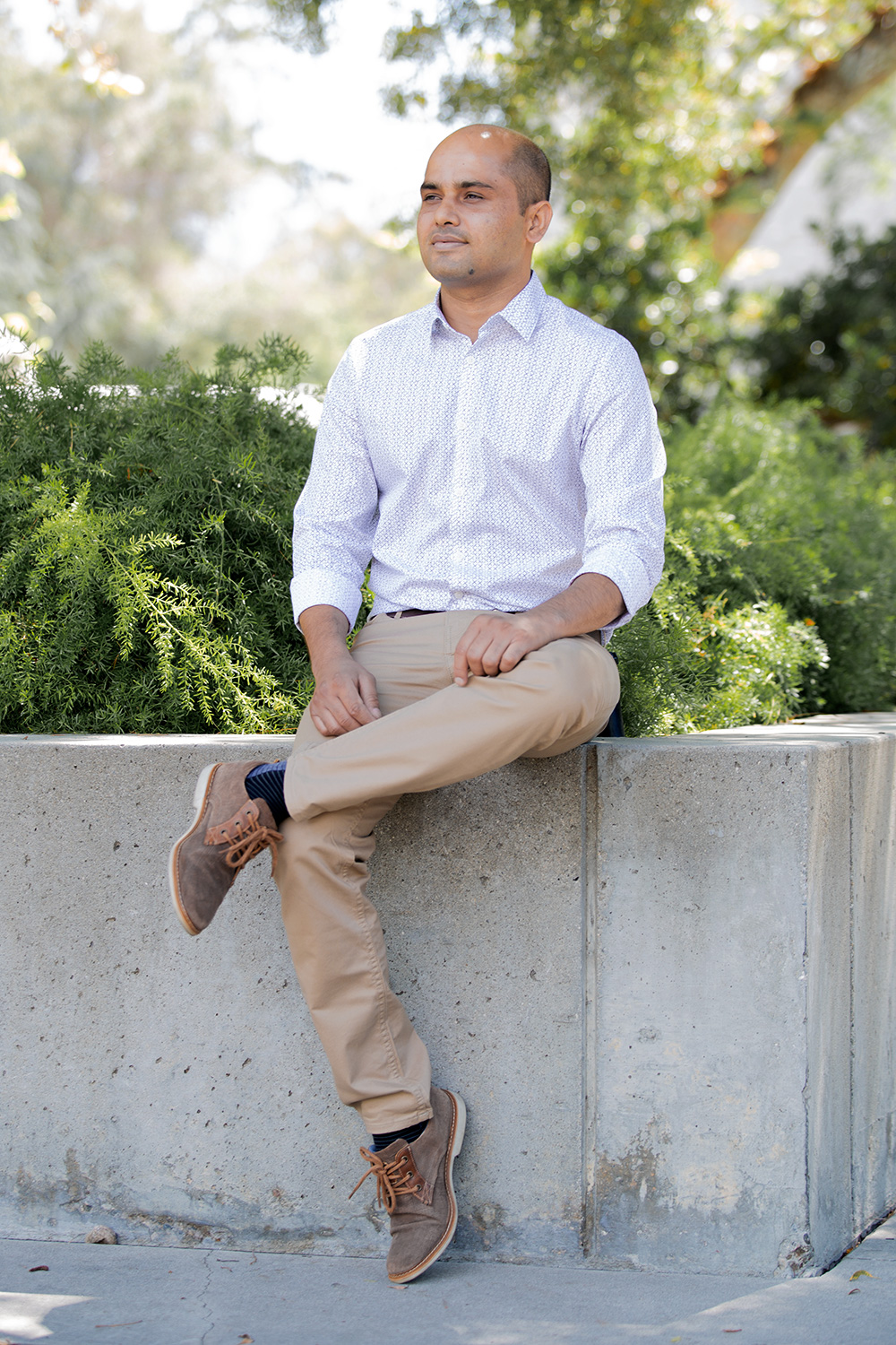 Surendra Adhikari sitting on a concrete planter on the JPL campus.